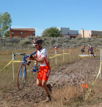 Cyclocross racers carry bikes through mud