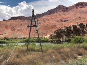 Measurement tower across a river with tawny desert rock bluffs in the background.