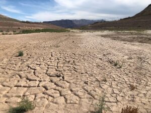 An apron of cracked mud in the foreground leads the eye to a distant Lake Mead.