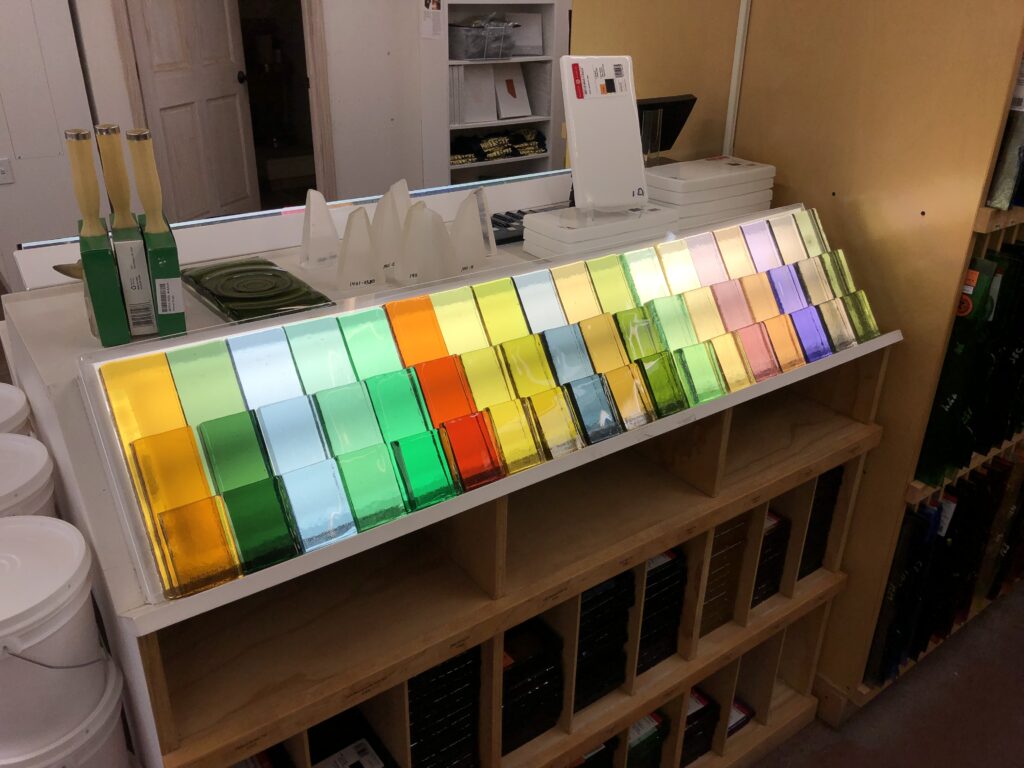 Blocks of colored glass lined up in an art store in many colors of the rainbow.