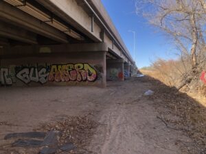 Concrete bridge leading into the distance, with trees and a blue sky.