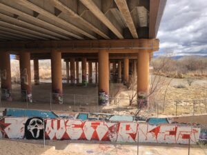 Graffiti on bridge abutments with river in background.